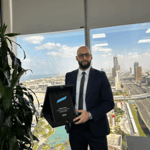 A Kaspersky representative holding the MENA Tech Editors' Choice 2025 award for Kaspersky Premium with Dubai skyline and cityscape in the background.