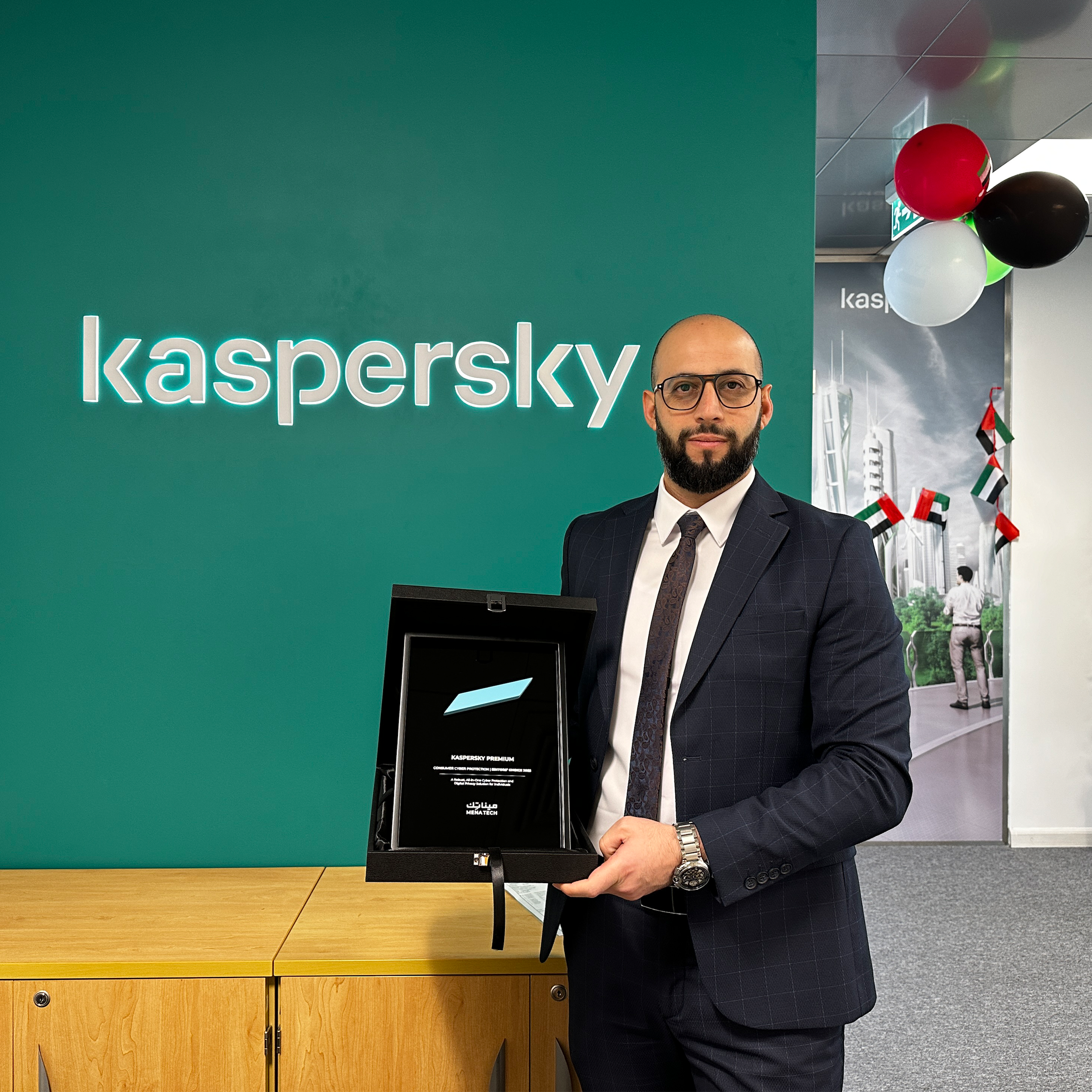 A Kaspersky representative holding the MENA Tech Editors' Choice 2025 award in front of the Kaspersky logo and UAE decorations.