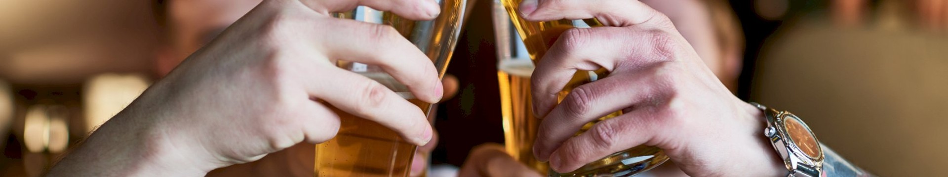 A group of lads on a beer themed stag do clinking their beers together