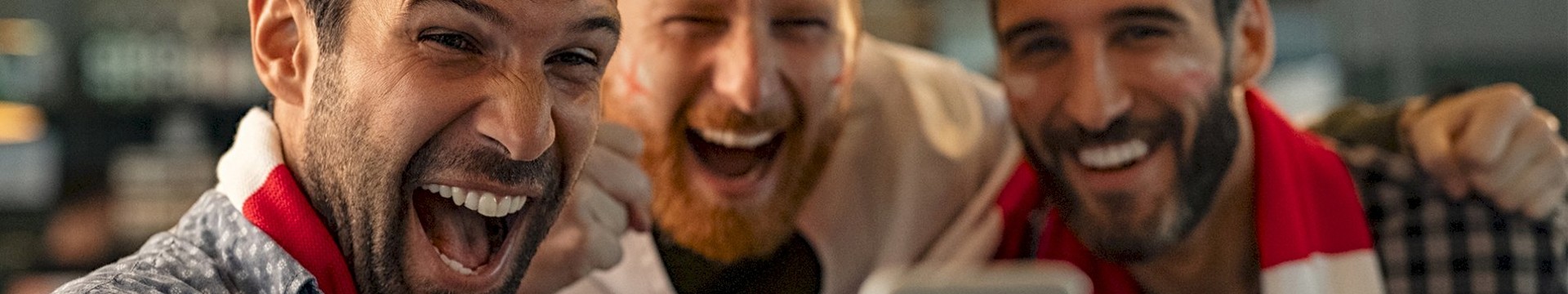 Three lads taking a picture with football scarfs.
