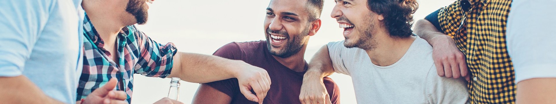 Five men enjoy beer on a beach on a stag weekend.