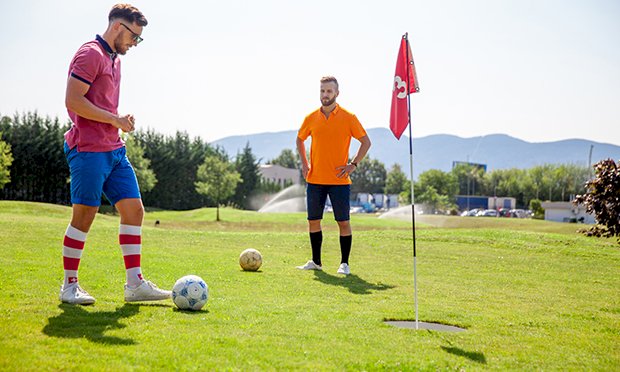 Two men taking part in footgolf.