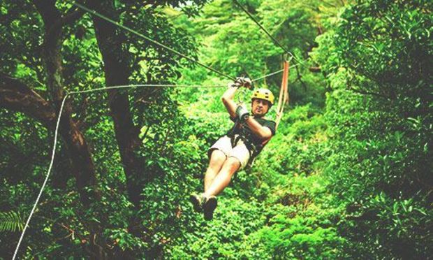 One man on a zip line in the forest. Discover the Albufeira High Ropes Course with Stag Weekends.