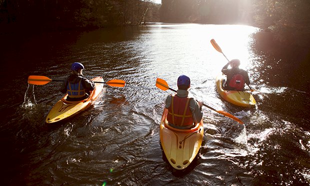 Three men taking part in kayaking on the river.