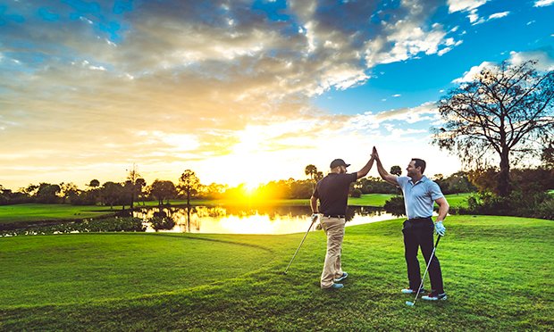 Two men high fiving on a golf range 