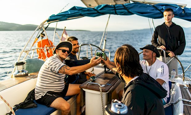 Five men enjoying beers on a sunset cruise.