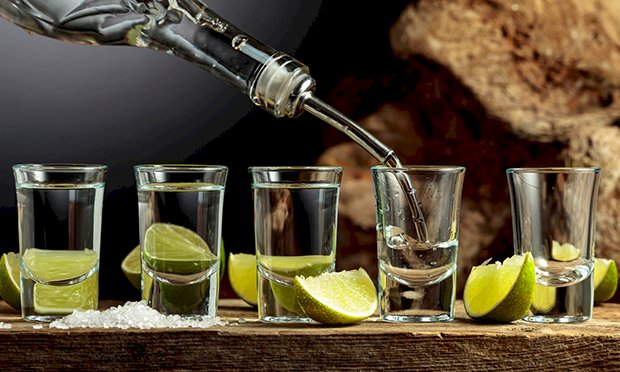 Four shots of vodka lined up with lime.