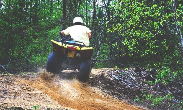 Male on quad bike going though the woods