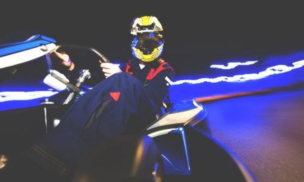 Man in go karting kit sitting inside a go kart.