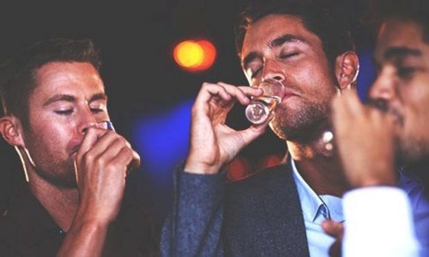 A group of lads taking shots in a pub, let in with club entry passes obtained because if their stag do celebration