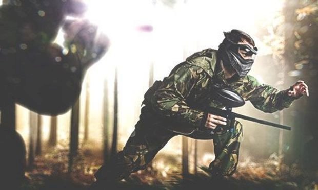 a group taking part in a paintballing activity as a part of a stag weekend 