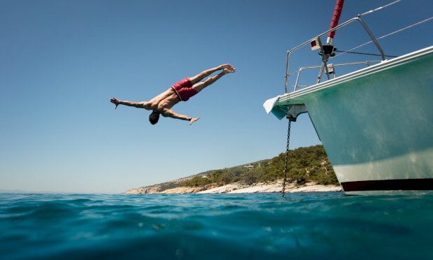 Man on a stag party jumping of a boat into the sea