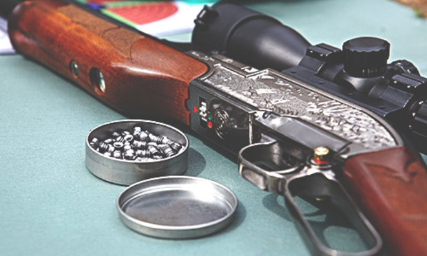 Rifle with a scope next to a round tin of ammo. Discover the Lincoln Air Rifle and Pistol Shooting stag party experience: