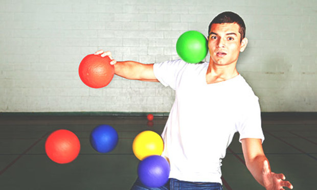 Guy in a white t-shirt and jeans getting hammered with dodgeballs. Discover the Lincoln Dodgeball stag party experience: