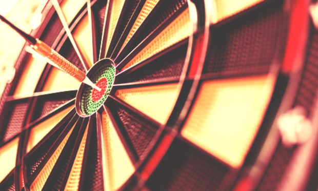 Red and yellow dart board with a dart in the bullseye. Discover the Lincoln Football Darts stag party experience: