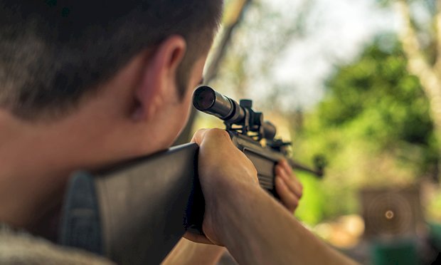 A man pulling back on an air rifle.