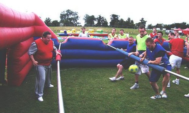 Men playing human table football in two teams