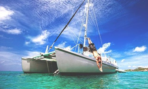Catamaran cruise in the middle of the crystal blue sea with a guy jumping off into the water