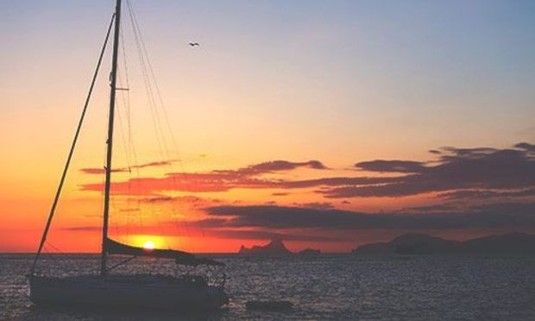 Orange sky over a sailboat on the Med. Discover Ibiza Stag Party ideas below: