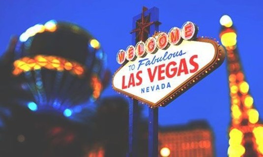 Lights from the Paris Las Vegas hotel shine behind the Welcome to Las Vegas sign. Explore Las Vegas Stag Party ideas below: