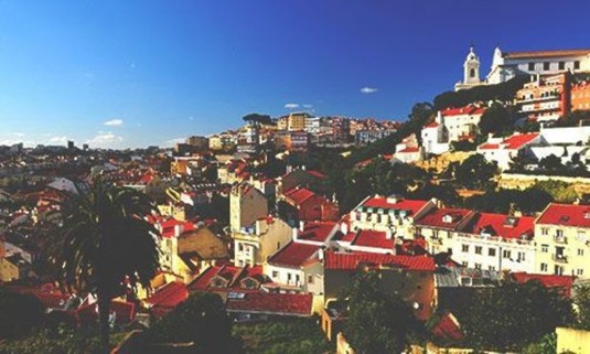 Red-topped buildings in Lisbon with a clear blue sky above. Discover Lisbon Stag Party ideas below: