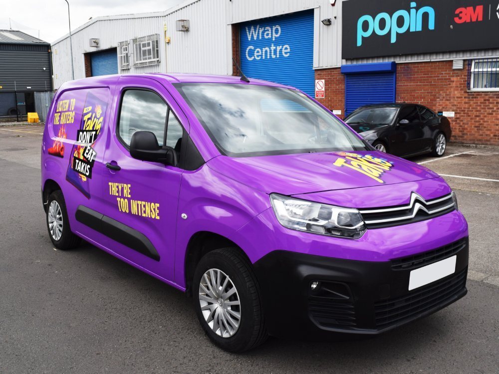 Marketing campaign graphics on a purple Citroen Berlingo company van.