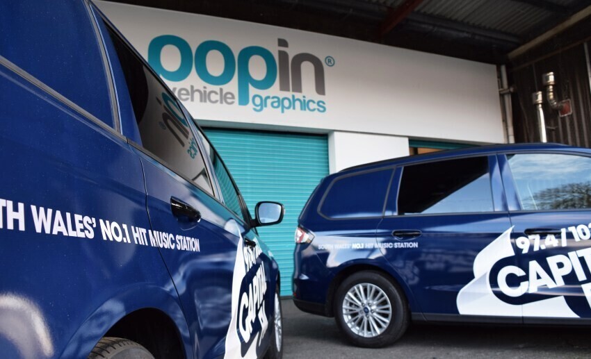 White branded vinyl graphics on blue company car fleet outside Popin in Cardiff.