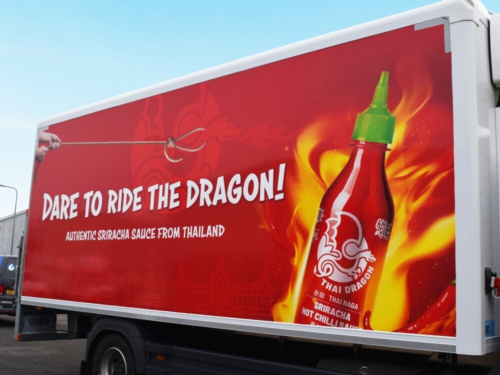 Red advertising vehicle wrap on a Mercedes truck trailer.