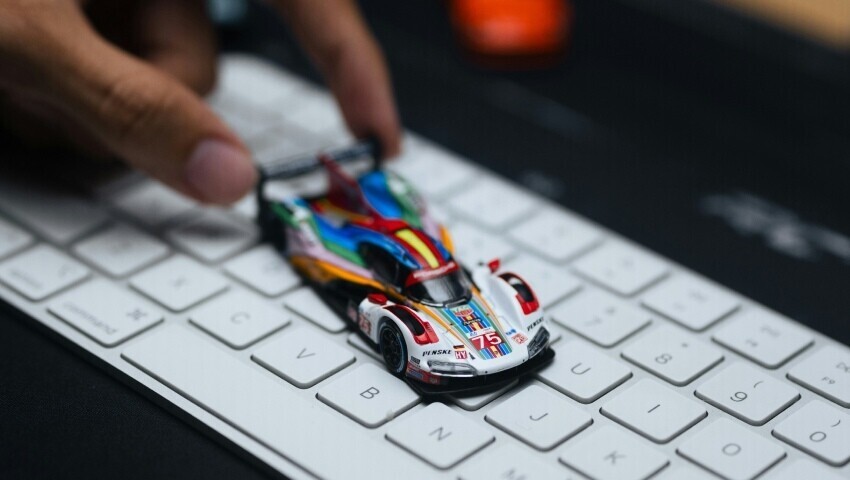 Toy race car being pushed along a computer keyboard.