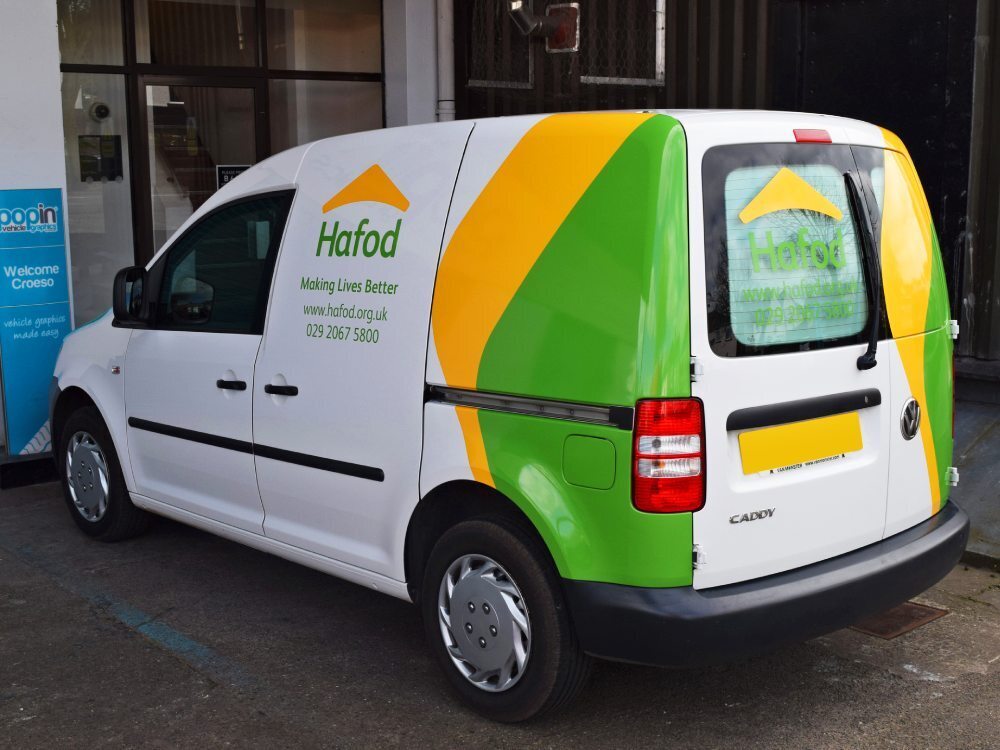 Green and yellow partial van wrap on white company Volkswagen Caddy.