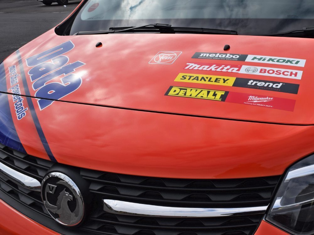 Company branded vinyl graphics on orange wrapped Vauxhall Vivaro business van.