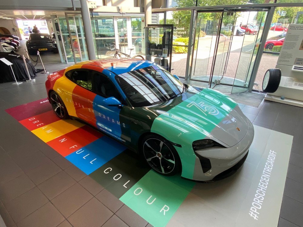 Vibrant motorsport wrap on a Porsche Taycan Turbo displayed in a Cardiff showroom