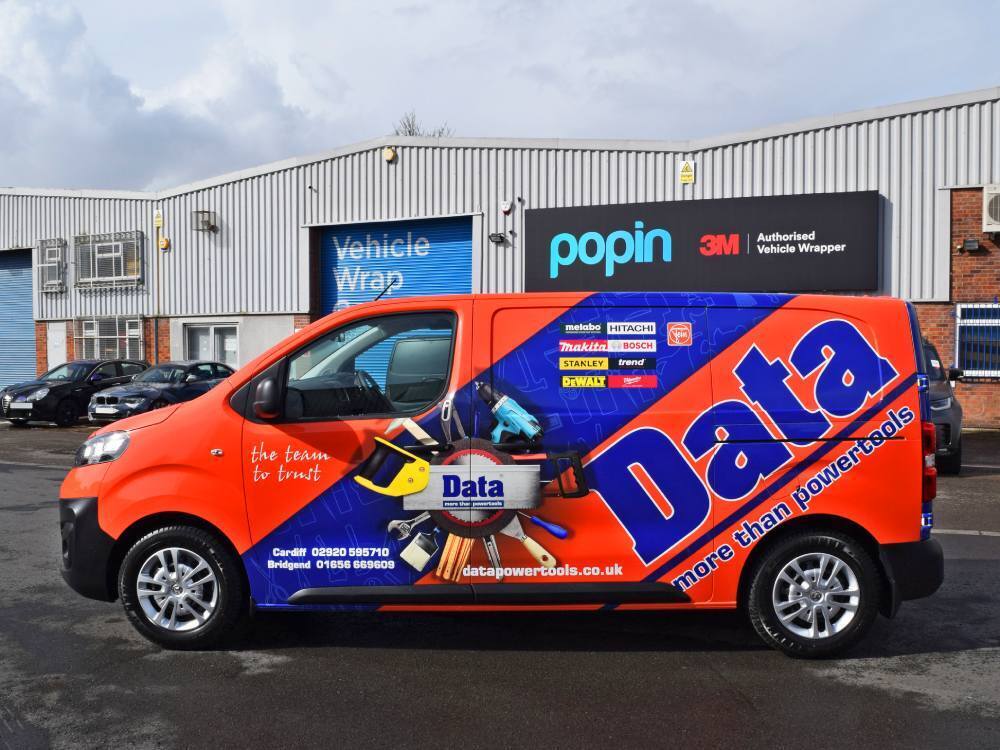 Bright orange and blue company branded van wrap on Vauxhall Vivaro outside Popin in Cardiff.