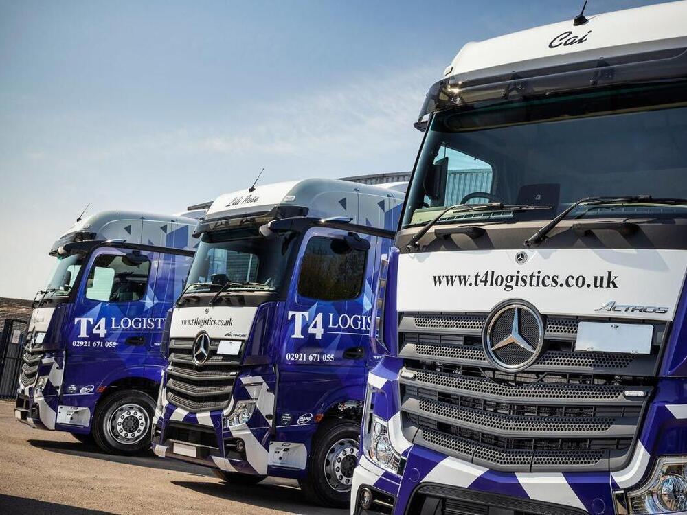 Fleet of three Mercedes trucks with matching blue and white branded vinyl wraps.