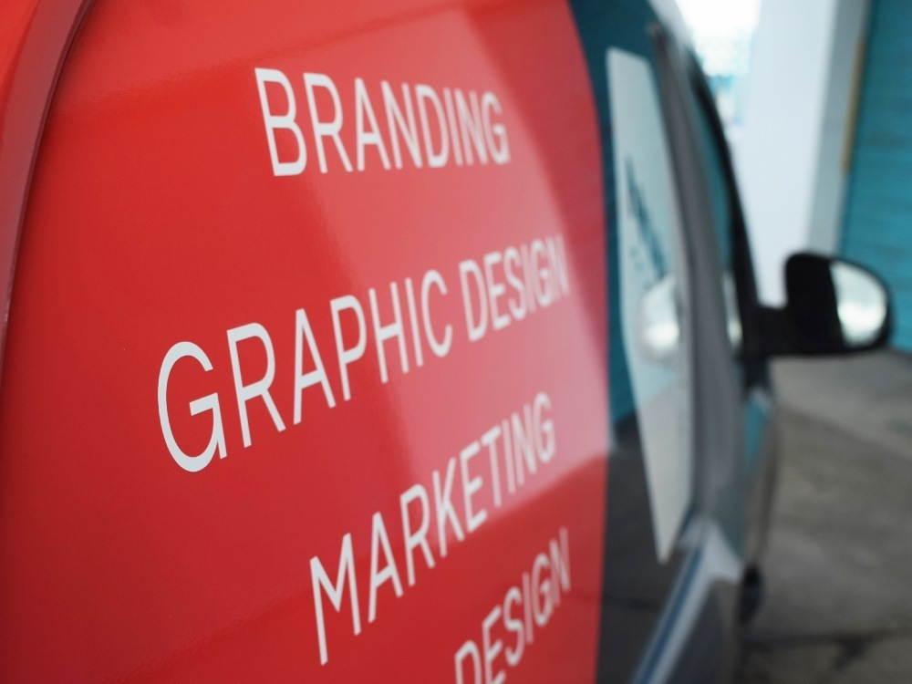 Close up of red vehicle wrap on Mercedes Company van.