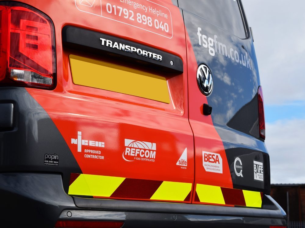 Vehicle vinyl graphics and chevron markings on wrapped company Volkswagen Transporter van.