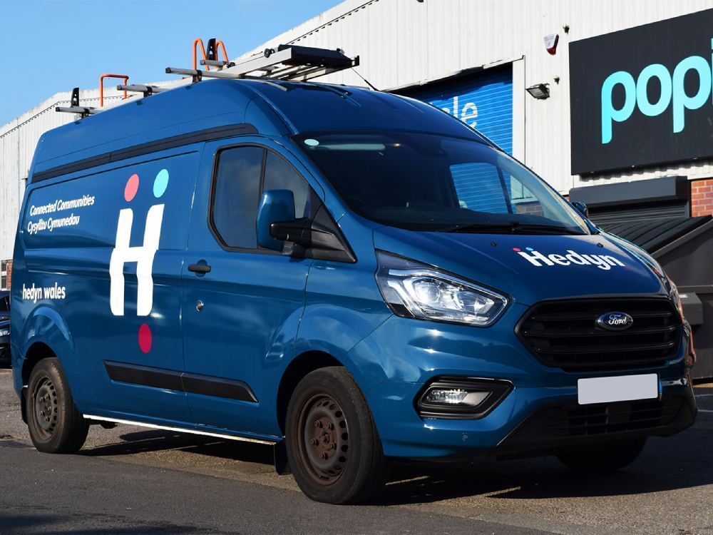 Blue company Ford Transit van with full vehicle wrap and graphics.
