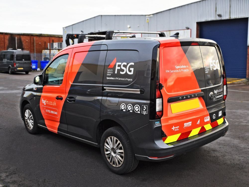 Partial van wrap with graphics and safety chevron markings on Volkswagen Caddy.