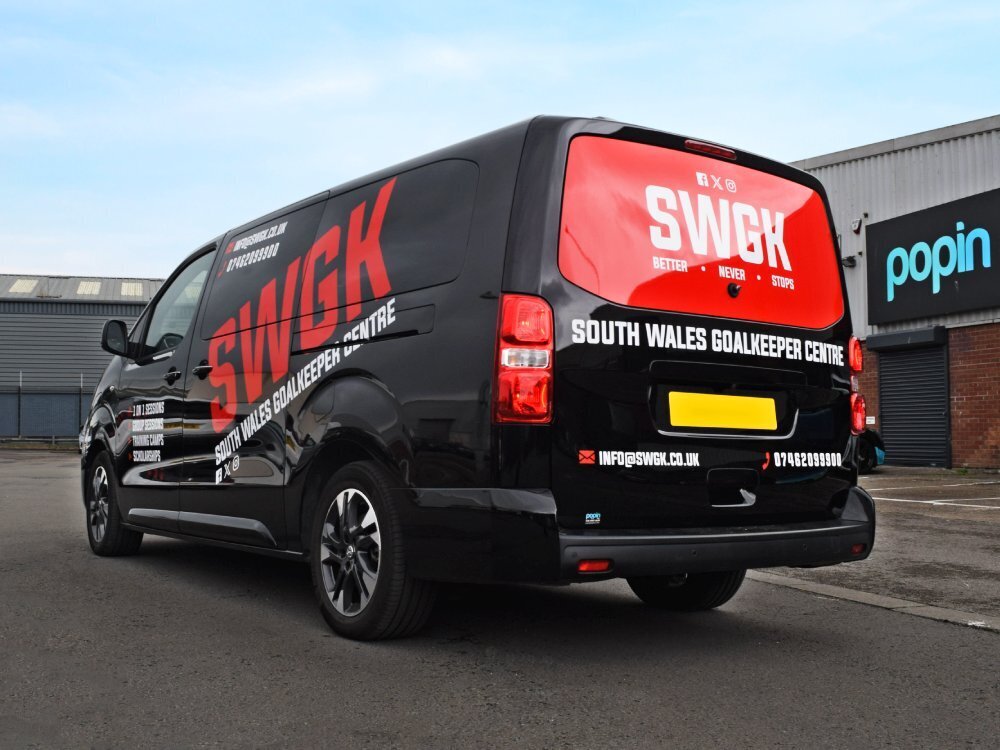 Red and white vinyl graphics on black company Vauxhall Vivaro van outside Popin wrap centre in Cardiff.