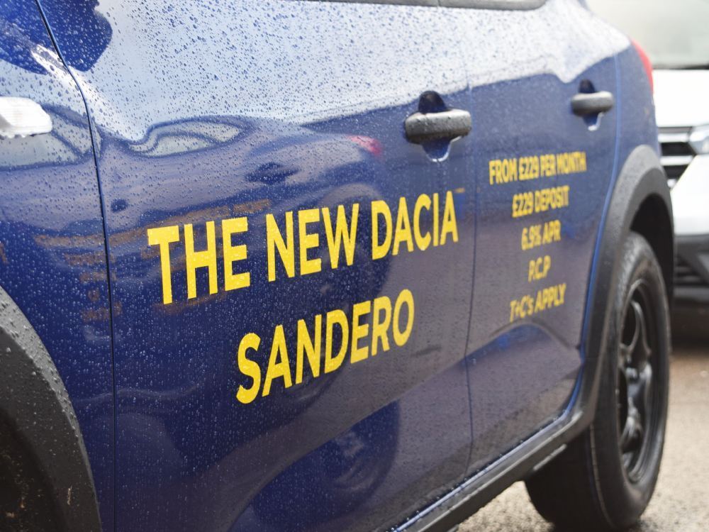 Close up of yellow vinyl graphics on a blue Dacia Sandero company car.