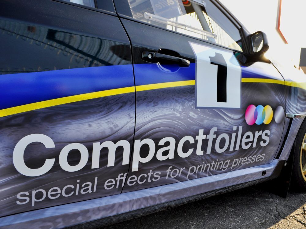 Close up details of a commercial wrap installed on the side of a Subaru Impreza B13 rally car