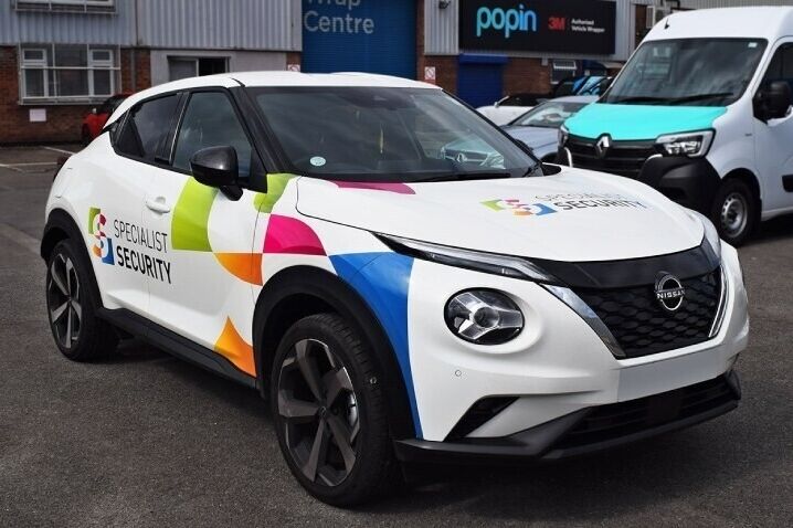 White company owned Nissan Juke with colourful branded partial vehicle wrap and graphics outside Popin in Cardiff.