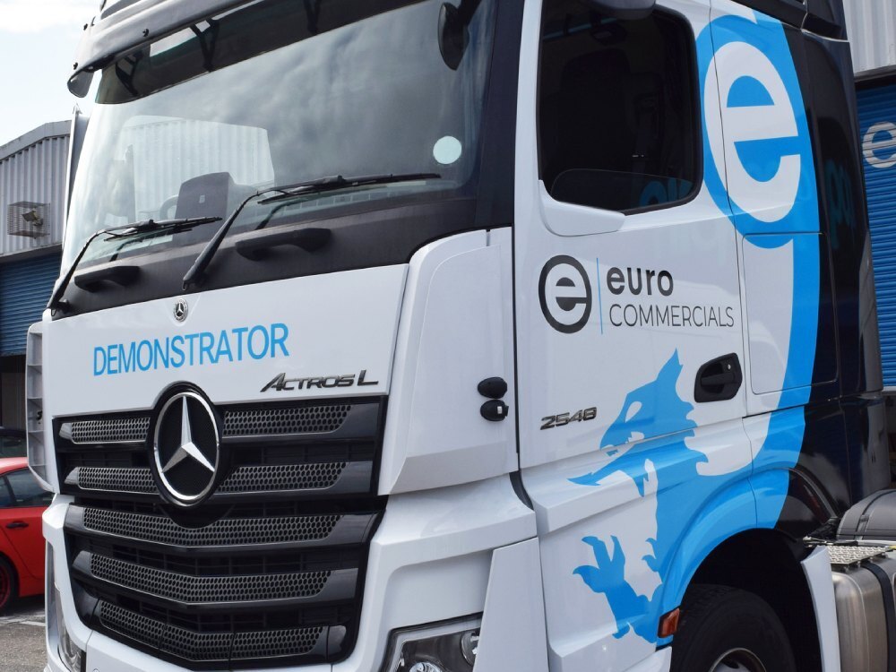 Branded vinyl wrap and graphics installed on a white company Mercedes lorry.