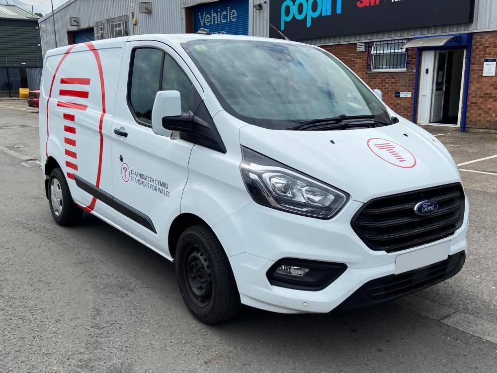 Transport for Wales branded vehicle graphics on white Ford Transit Custom company van.