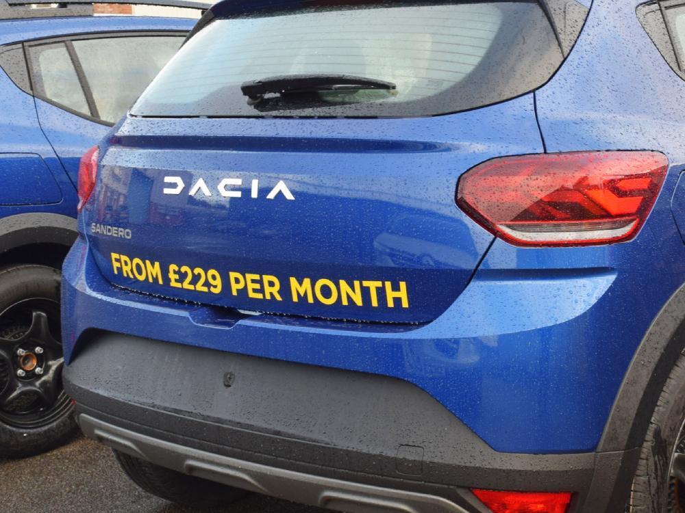Yellow vinyl graphics on rear end of blue company owned Dacia Sandero car.