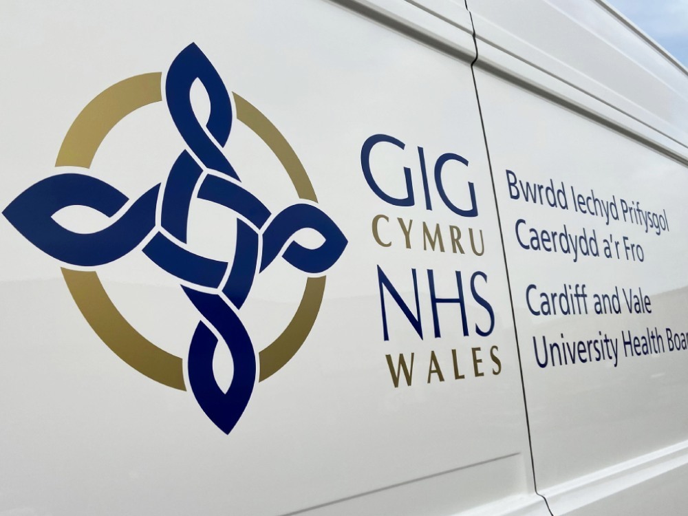NHS logo vinyl graphics on side of white Volkswagen Crafter van.