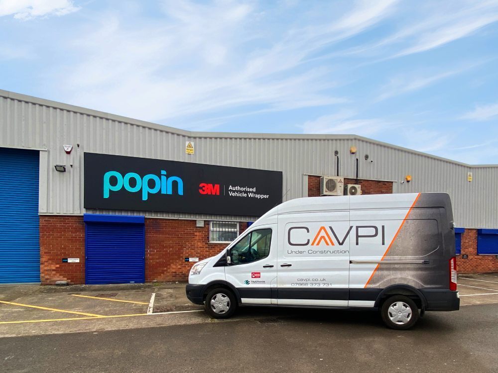 Company branded partial vehicle wrap and vinyl graphics on white Ford Transit van.