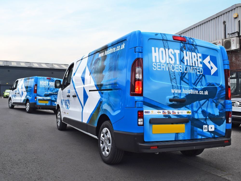 Fleet of Renault Trafic company vans with matching blue partial van wraps.