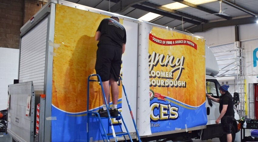 Popin installation technicians installing a vehicle wrap onto the side of an Iveco Daily Box van.