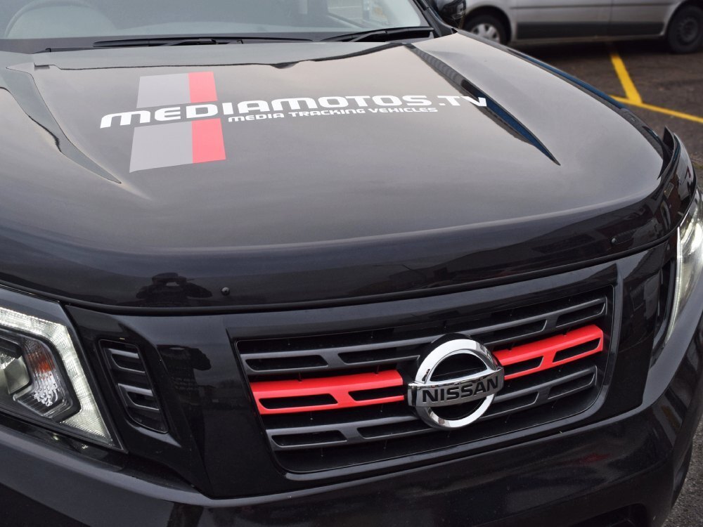 Branded vehicle graphics on bonnet and red grille trim on front of black company Nissan Navara.